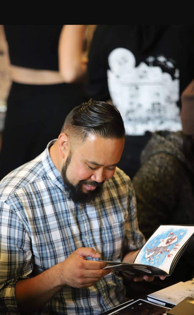 Image of Vincent Kukua smiling as he looks at a book in his hand