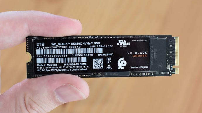 WD černý SN850X SSD, který je držen mezi prstem a palcem