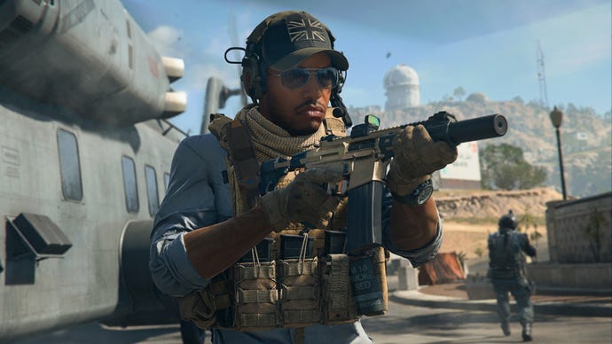 Gambar Warzone 2 yang menunjukkan Gaz menggunakan senapan serbu chimera, berdiri di sebelah helikopter besar di Al Mazrah