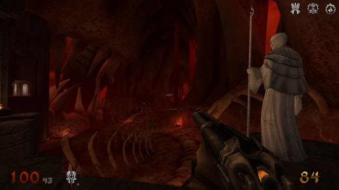 تصویری از فیلم Wrath: Aeon of Ruin، که بازیکن را در داخل یک ناحیه هاب بزرگ ساخته شده از گوشت و استخوان، نشان می‌دهد که در کنار یک چهره سفید و طاس ایستاده است که چوبی را در دست دارد.