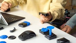 Various Xbox Adaptive Accessories on a table, one being held by the user.