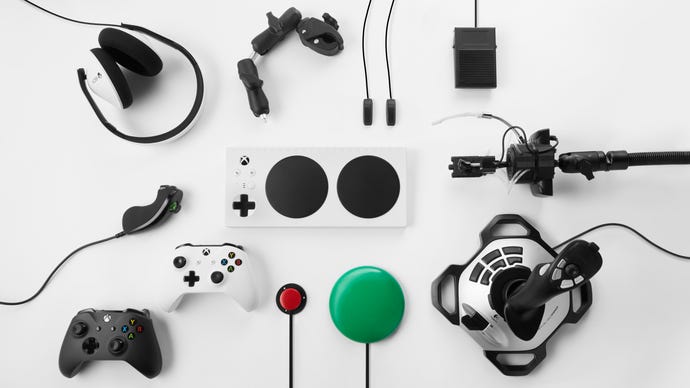 The Xbox Adaptive Controller, surrounded with compatible peripherals including buttons, joysticks, an Xbox gamepad, and a headset.