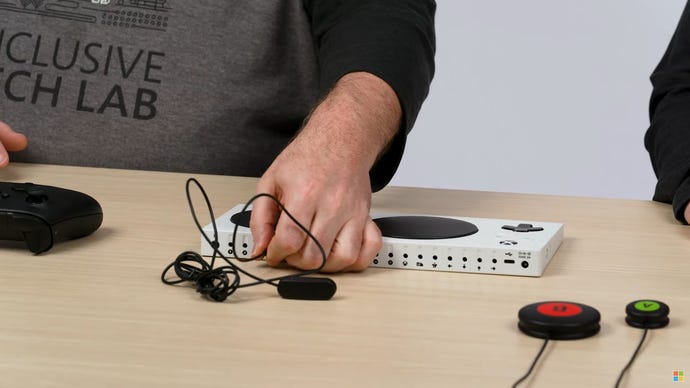 An a button being plugged into one of the 3.5mm ports on the back of an Xbox Adaptive Controller.