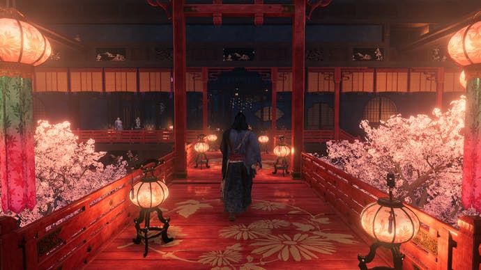 Capture d'écran officielle de Rise of the Ronin montrant le joueur marchant vers l'entrée d'un bâtiment japonais traditionnel rouge vif et rose