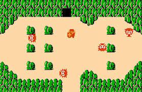 Link faces off against several enemies in a sandy stretch of land surrounded by green mountains. There's a cave entrance at the top of the screen.