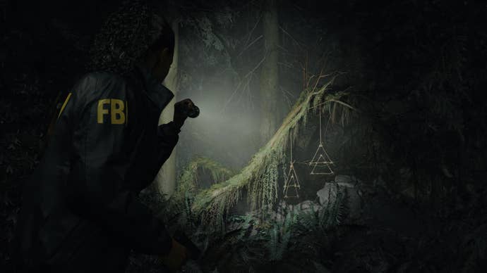 In this screenshot from Alan Wake 2, FBI agent Saga Anderson points a flashlight into a dark wooded depths