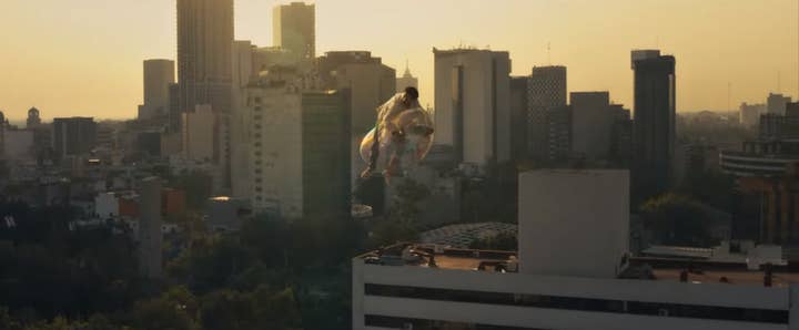 A man rides a floating bubble high above a city, skyscrapers are visible in the background