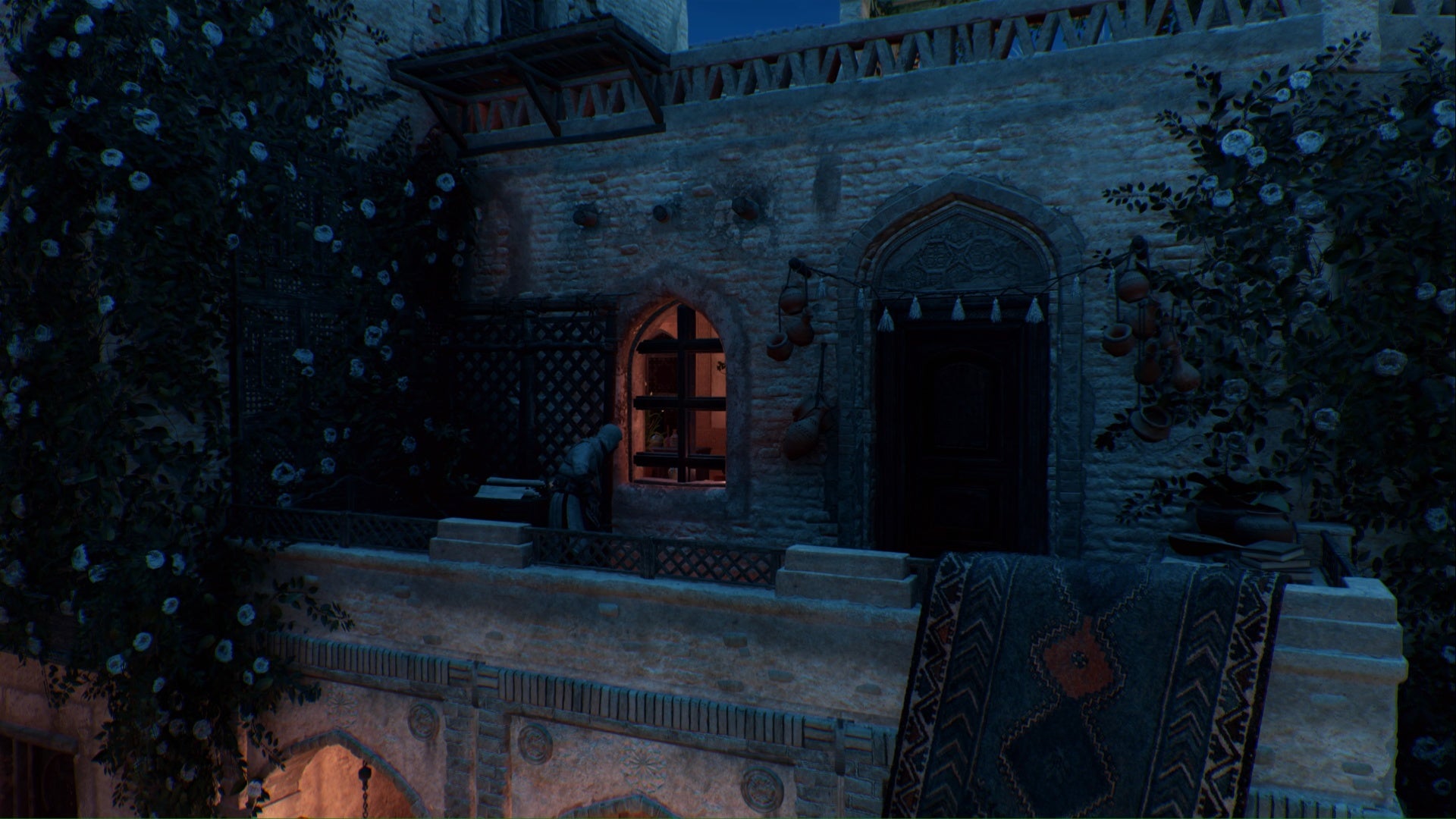 En Assassins Creed Mirage, Basim está parado en un balcón de piedra mirando el interior de un edificio a través de una ventana.