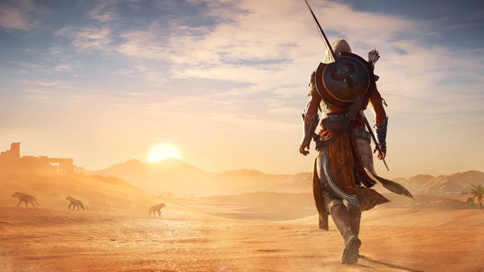 An assassin looks out over a sandy desert in Assassin's Creed Origins