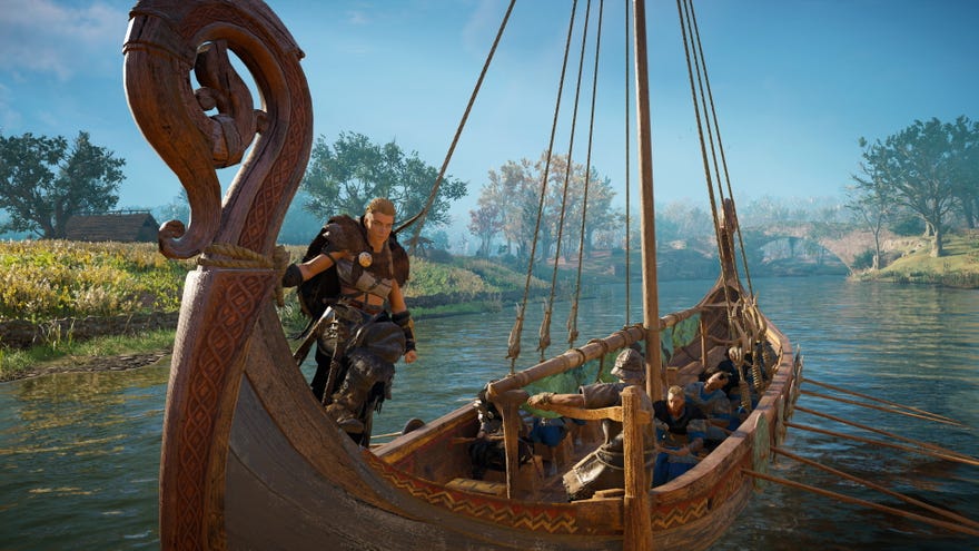 Assassin's Creed Valhalla - Eivor stands at the front of a boat while other vikings row and steer.