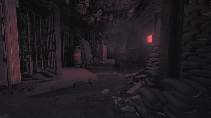 Amnesia: The Bunker review screenshot, red light casts a bloody sheen on sandbags, gas tanks, and broken items strewn across the floor.