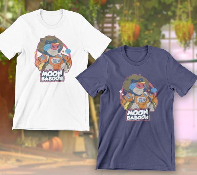 White and blue merch t-shirts for It Takes Two, both with a Moon Baboon logo of a toy baboon in a space suit