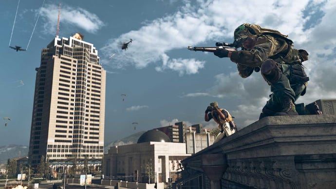An image of Die Hard's Nakatomi Tower in Warzone, and just off to the side, a player aims down a sniper rifle, while another looks through some binoculars behind them.