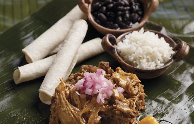 Photograph of a meat dish with tortillas and rice and beans