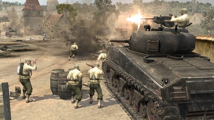 सैनिक नायकों की कंपनी में एक टैंक के बगल में खड़े हैं