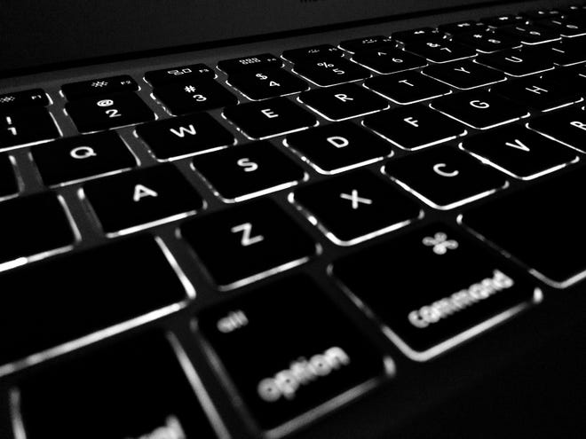 Closeup photograph of a backlit black laptop keyboard