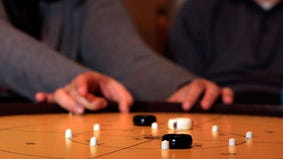A player takes a shot in dexterity game crokinole