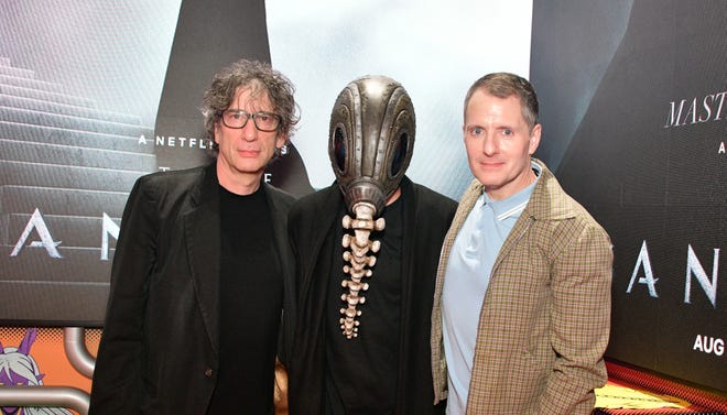 Image of Neil Gaiman and Allan Heinberg with masked figure at Sandman Press event