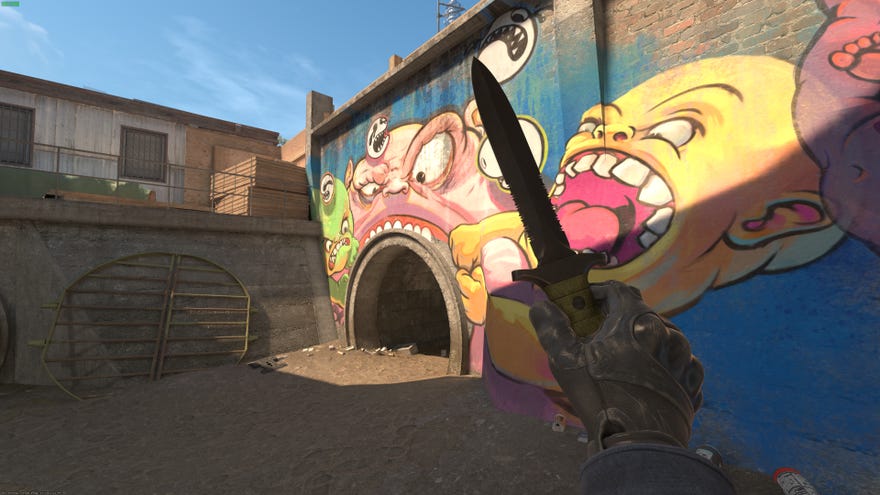 A player in Counter-Strike 2 inspects their knife in front of a wall with colourful graffiti on it.