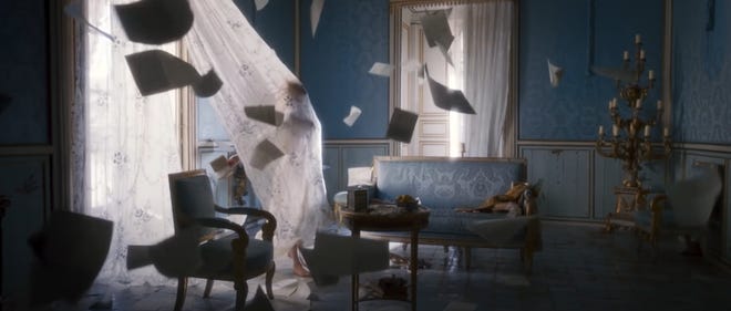 Still image of Roxanne walking towards a curtain with letters flying through the air
