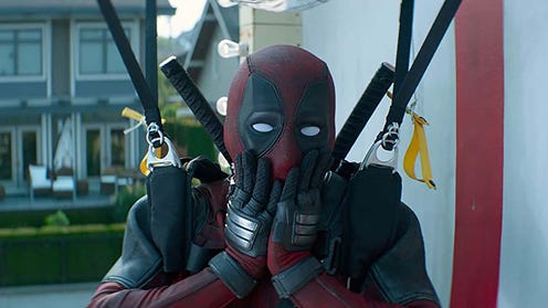 A man in a Deadpool costume with his hands on his face in mock surprise. Deadpool 2 still