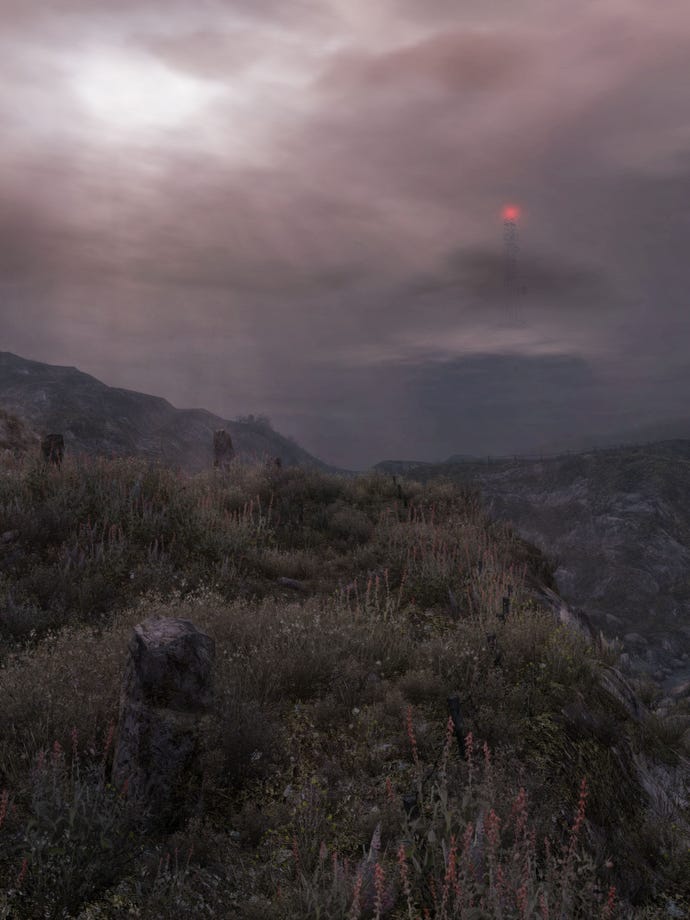 A screenshot of Dear Esther showing the rocky landscape of the island, with patchy heather and grass, and the red light on top of the beacon tower in the foreground
