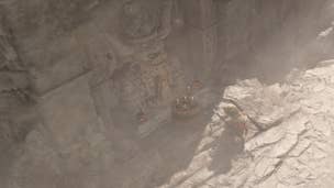 Diablo 4 keeping the old traditions solution: A man in a turban and a green skirt is standing on dry rock in front of a brace of skulls carved into stone