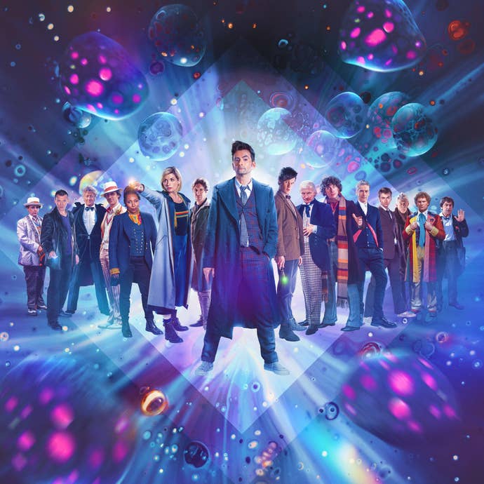 All 14 Doctor Whos stand in a line, with David Tennant in the middle, but also appearing as his younger self to the right of the lineup.