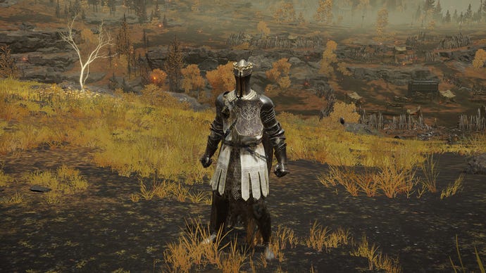 Играчът в Елдън Ринг стои пред камерата, носещ комплекта Haligtree Knight Armor. Зад тях е гледка към платото Алтус
