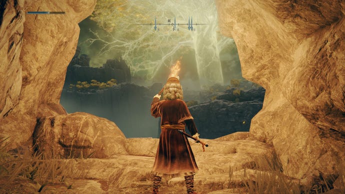 Elden Ring player holding a torch as they leave Coastal Cave, Great Erdtree towers in the horizon
