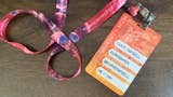 A card-sized, orange Summer Game Fest press pass connected to a pinkish lanyard, placed on a table.