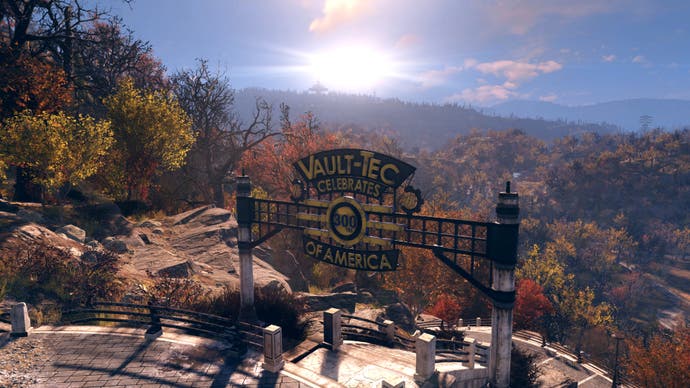 Fallout 76 State of the Game - official image showing the Vault Tec iron gates on a precipice overlooking forest, blue skies and glowing sun in the distance