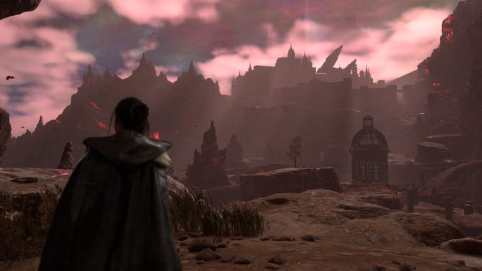 Frey, Protagonist of Forspoken, stands looking at a forbidding black and grey rocky landscape, a castle off in the distance. There are red clouds in the sky, and red particles floating in the air
