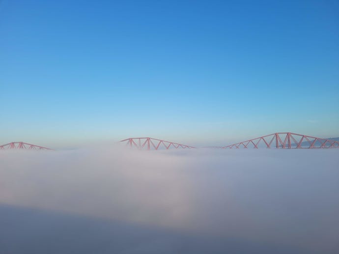 A photograph of the Forth Bridge emerging from thick cloud.