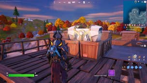 Fortnite Oathbound Chests: An animated character in pointy black armor stands on a wooden platform. In front of him is a large silver chest resting on two wooden boxes.