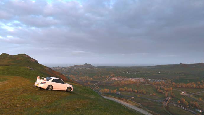 A white car sits on a mountaintop, overlooking the wild UK countryside in Forza Horizon 4.
