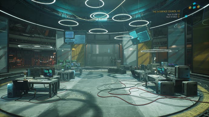 The inside of your base in Ghostrunner 2. It's a cyberpunk office - or at least it looks like one. There are half-a-dozen desks with computers on, and thick wires trailing around the floor. The whole circular class interior is lit by circular lights from the ceiling, bathing it in a bluey, greeny glow.
