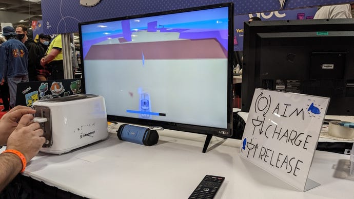 A person uses a toaster to control an in-game toaster in a toaster-fish-golfing game at GDC