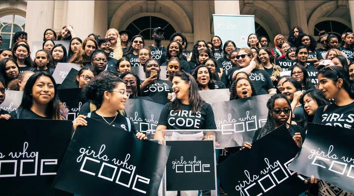 Group picture of women in Girls Who Code t-shirts holding up signs for the organization