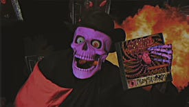A purple skeleton in a black cape and hat holds a CD case labelled "Haunted PS1"