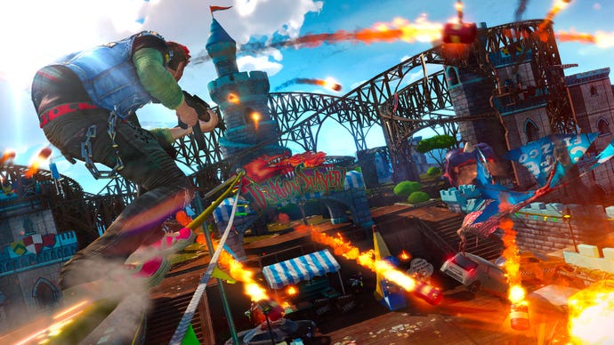 A screenshot from Sunset Overdrive, which shows players traveling on theme park tracks as explosions and rockets whirl around them.