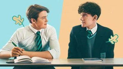 Netflix Heartstopper Key Art Charlie and Nick are looking at each other, sitting at a school desk in their uniforms