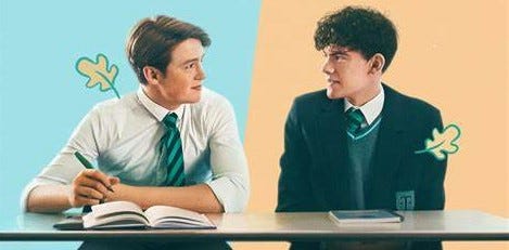 Netflix Heartstopper Key Art Charlie and Nick are looking at each other, sitting at a school desk in their uniforms