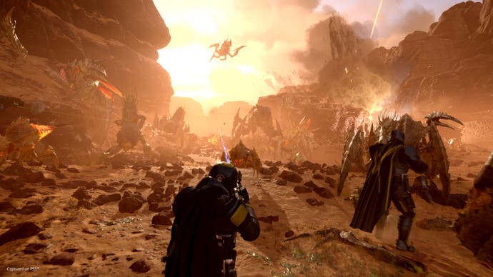 A Helldivers 2 screenshot showing players battling armies of scuttling and flying aliens on a hostile desert planet.