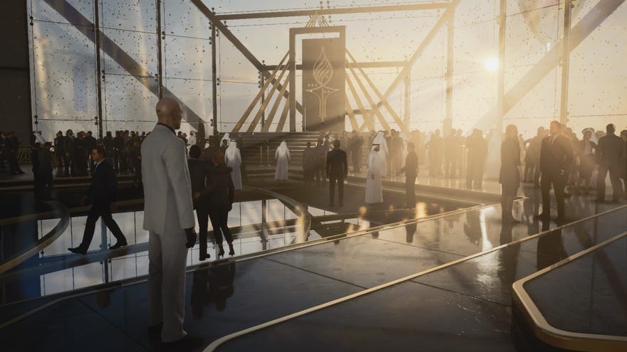 A screenshot of Agent 47 standing in a large glass atrium from Hitman 3's Dubai level