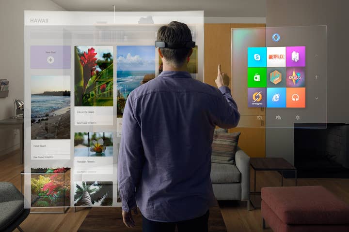 A HoloLens-wearing man with his back to the camera raises a hand to interact with virtual screens, one showing a variety of photos, another showing different apps