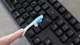 A keyboard being dusted with a toothbrush.