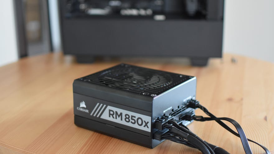 A Corsair RM850X PSU in front of an opened PC.