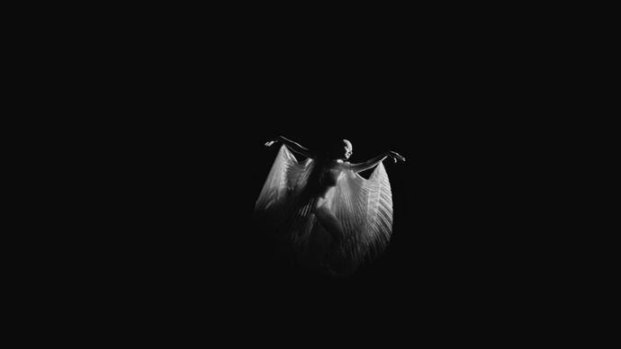 A woman dances in a see through floaty cape, in a black void, from a clip from Immortality