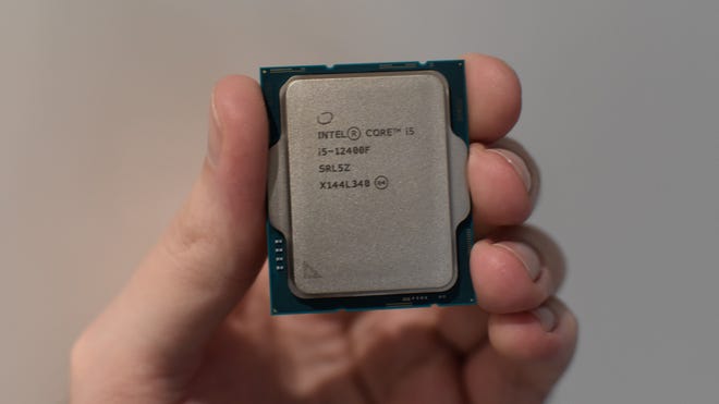 An Intel Core i5-12400F CPU being held in a hand.